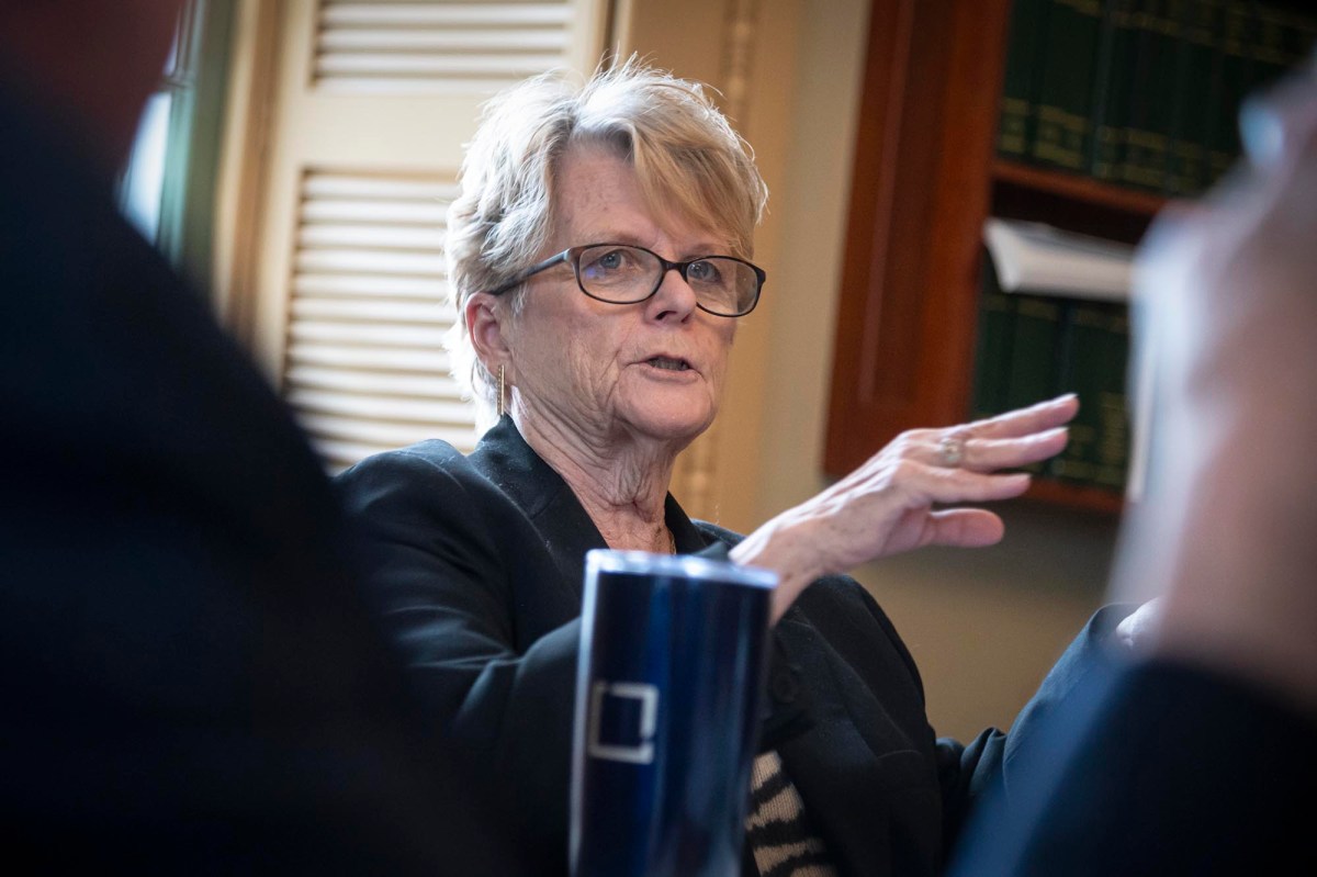 A woman with glasses is talking to a group of people.