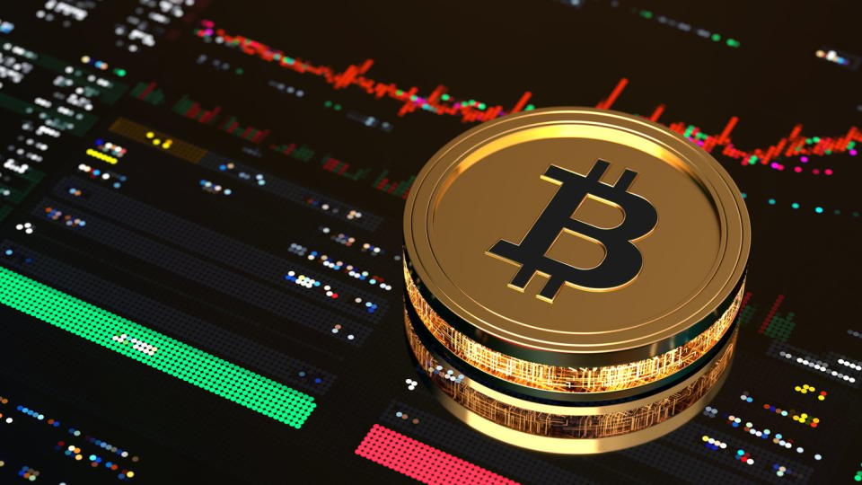 Gold Bitcoin on top of a stock market trading screen.